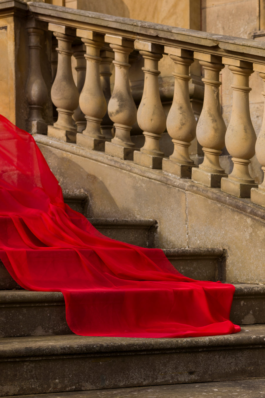 Red fabric draped over stone steps with a classical building in the background