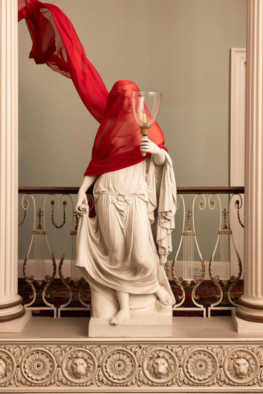 Statue with a red cloth draped over its head in an ornate indoor setting