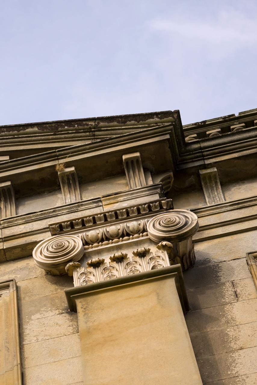 Decorative stone cornice on a building facade with a clear blue sky.